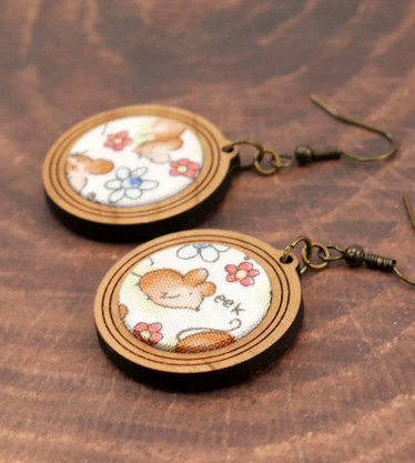 Closeup of round fabric and wood earrings with mice saying eek