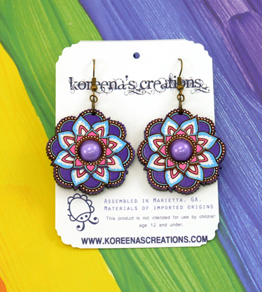 Primarily purple flower mandala earrings on rainbow background