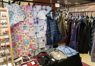 Craft show display showing rag rug quilts and upcycled aprons